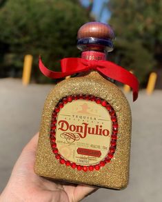 a hand holding a small bottle with a red ribbon around it's neck that says donjullo