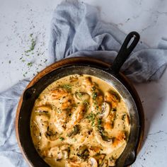 a skillet filled with chicken and mushroom gravy on top of a table