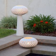 two white lights sitting on top of cement steps next to a planter and potted plants