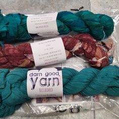 three skeins of yarn sitting on top of each other in plastic wrappers