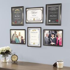 a desk with some pictures hanging on the wall and a clock in front of it