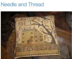 a needle and thread pillow sitting on top of a wooden table next to a tree