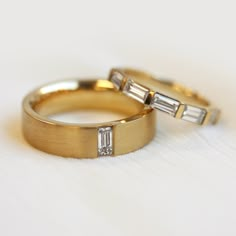 two gold wedding rings with baguettes on top