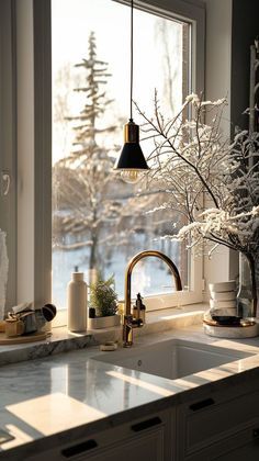 a kitchen sink sitting under a window next to a counter top covered in frosted branches