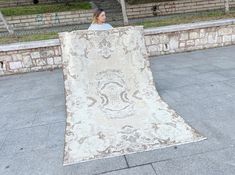 a woman sitting on the ground with a large rug in front of her and looking at it