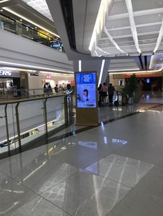 an airport lobby with people walking around and on the escalator in front of them