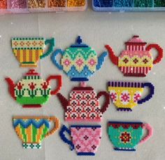 cross stitched teapots and cups on a table with bead sprinkles