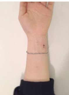 a woman's wrist with a small cross tattoo on the left side of her arm