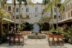 tables and chairs set up in front of a building with palm trees on either side