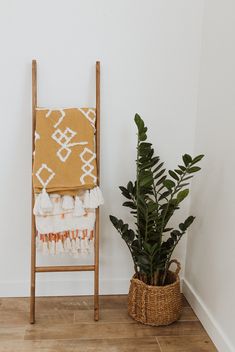 a wooden chair sitting next to a potted plant on top of a hard wood floor