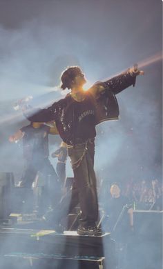 a man standing on top of a stage with his arms outstretched