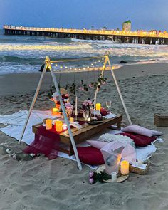 a table set up on the beach with candles