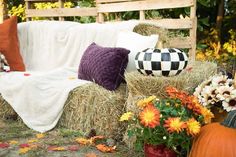 a couch covered in hay next to pumpkins and flowers