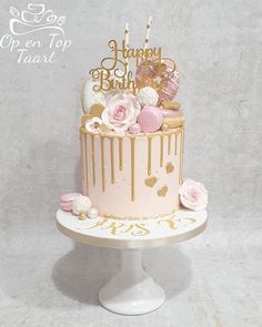 a pink and gold birthday cake with flowers on top