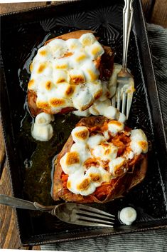 two pieces of baked potatoes covered in cheese and sauce with a fork on the side