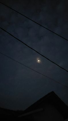 the moon shines brightly in the dark sky above some power lines and telephone poles