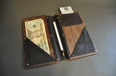 two leather wallets with money and pen on top of each other in front of a gray wall