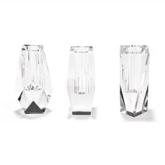 three crystal vases sitting next to each other on a white surface with no one around them