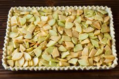 an uncooked apple pie sitting on top of a wooden table