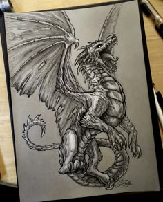 a drawing of a dragon with wings on it's back, sitting on top of a table