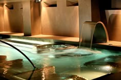 an indoor swimming pool with water running from the faucet to the side and lights on