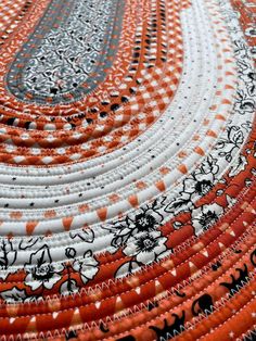 an orange, white and black table cloth with flowers on the edge is shown in close up