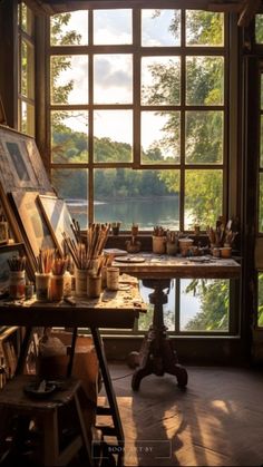 an artist's studio with large windows and lots of art supplies on the table