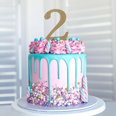 a birthday cake with pink and blue icing, sprinkles and a number two on top