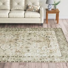 a living room area with a couch, coffee table and rug on the hardwood floor