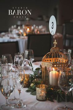 a birdcage filled with candles sitting on top of a table covered in wine glasses