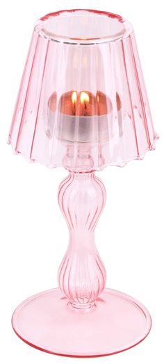 a pink glass table lamp with two lit candles in the bottom and one light on top