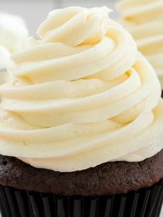 two cupcakes with white frosting sitting on a plate