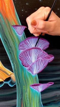 a person is drawing flowers on a piece of paper with colored pencils in their hand