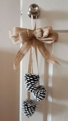 two pine cones tied to a door hanger with a bow on the front door