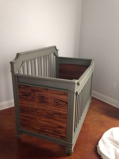 a baby crib in the corner of a room with a blanket on the floor