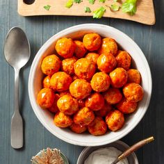 a white bowl filled with meatballs next to a cutting board and utensils