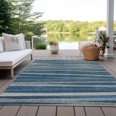 a blue and beige striped rug sitting on top of a wooden floor next to a white couch