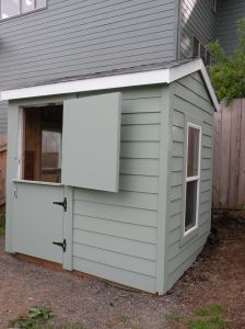 a small gray shed with a window on the side