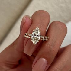 a woman's hand holding an engagement ring with a diamond on the top and side