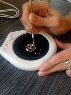 a person is using a pen to write something on a white object with black paint