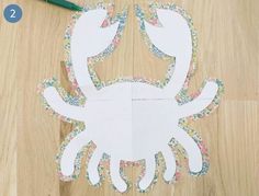 cut out paper crab sitting on top of a wooden floor next to a green marker