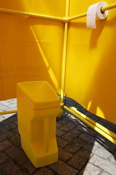 a yellow toilet sitting next to a yellow fence