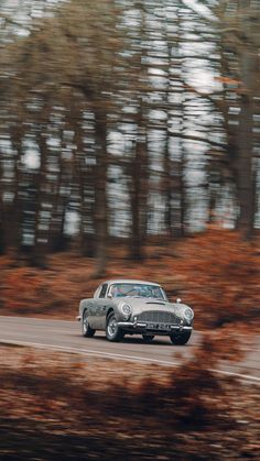 an old car driving down the road in front of trees