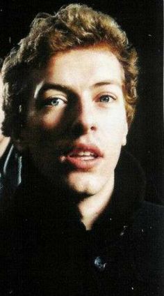 a close up of a person wearing a black shirt and looking at the camera with a serious look on his face