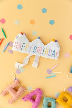 a happy birthday sign is surrounded by confetti and streamers on a yellow background