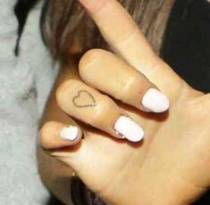 a woman's hand with a heart tattoo on her thumb and the middle finger