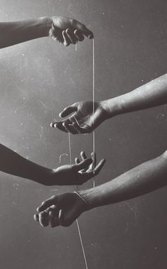 four hands reaching for string attached to strings