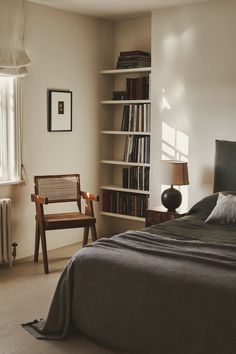 a bedroom with a bed, chair and bookshelf