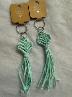 two green tasselled key chains with wooden tags attached to them