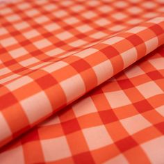 an orange and white checkered tablecloth is folded on top of the other cloth